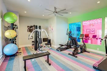 fitness center at Mandarin bay Apartment complex in Jacksonville, FL with cardio and weight machines and a colorful floor